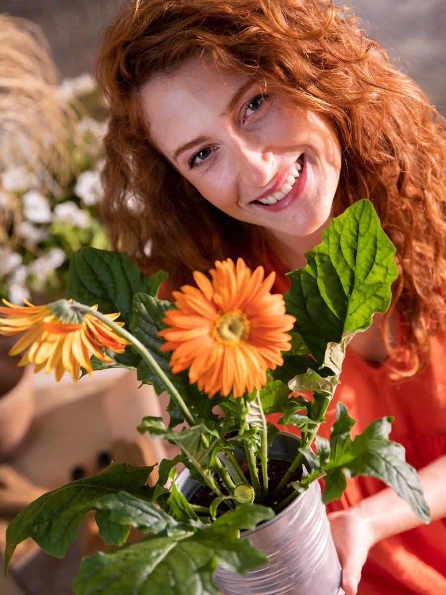 Happy woman with a pot of flowering plant Happy woman with a pot of flowering plant